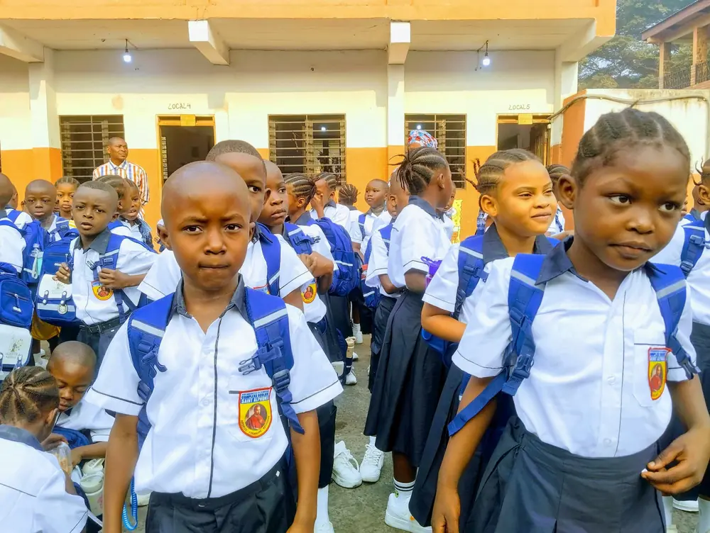 Des élèves souriants en uniforme, cartable au dos, le jour de la rentrée